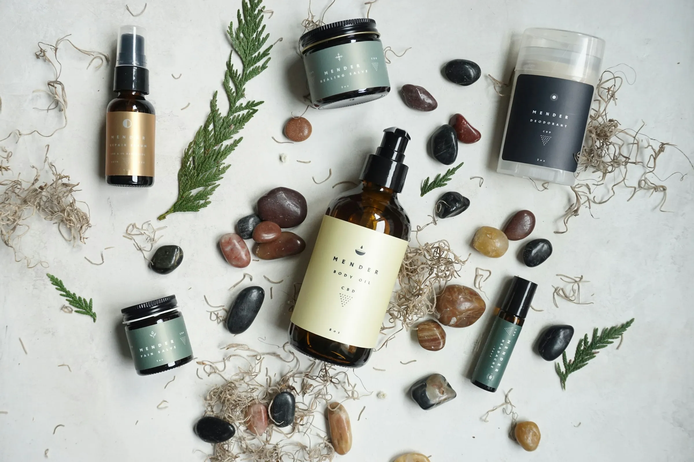 Naturkosmetik-Komposition mit Pflegefläschchen, Steinen und Pflanzenelementen